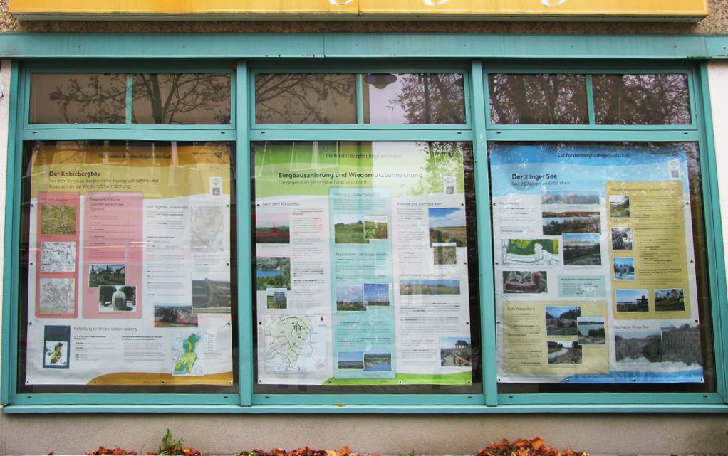 Schaukasten mit drei Infotafeln zu Kohlebergbau, Bergbausanierung und Klinger See hinter Glas.